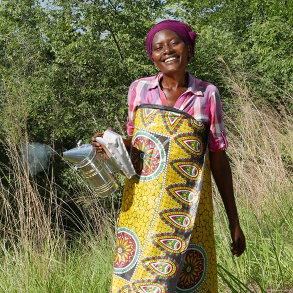  Happy African woman beekeeper holding smoker and bellows